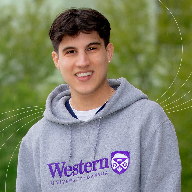 Demo Kaltabanis sitting outside in front of greenery with white Western impact lines behind.