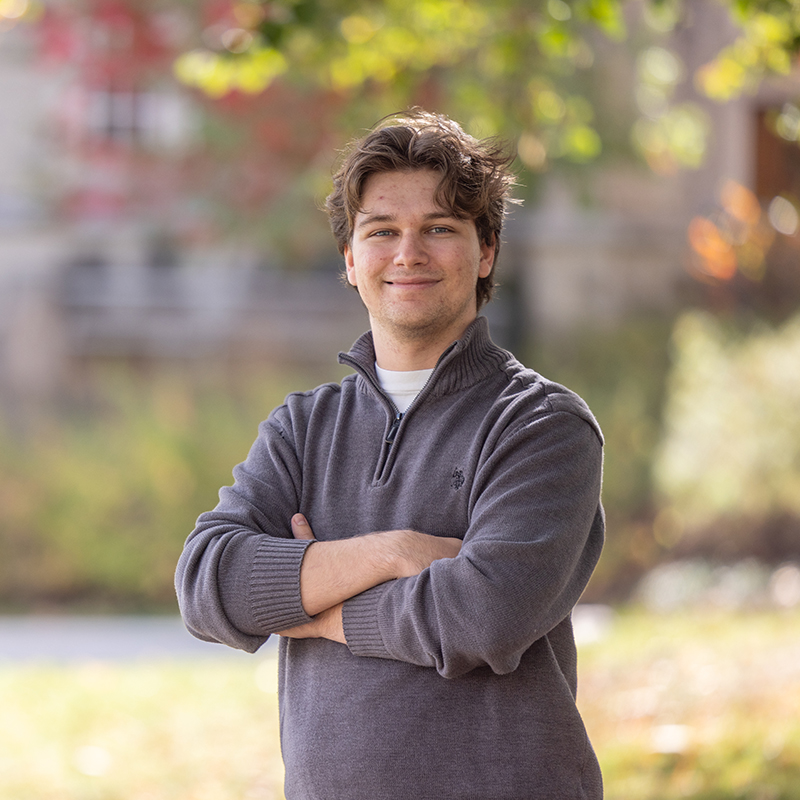 Person smiling outdoors while sitting on steps