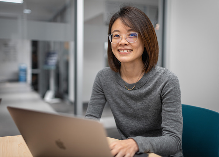 Person smiling while using a laptop