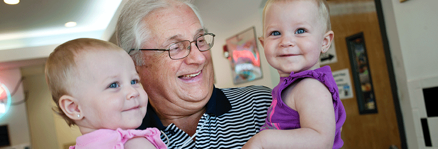 elderly man holding two babies