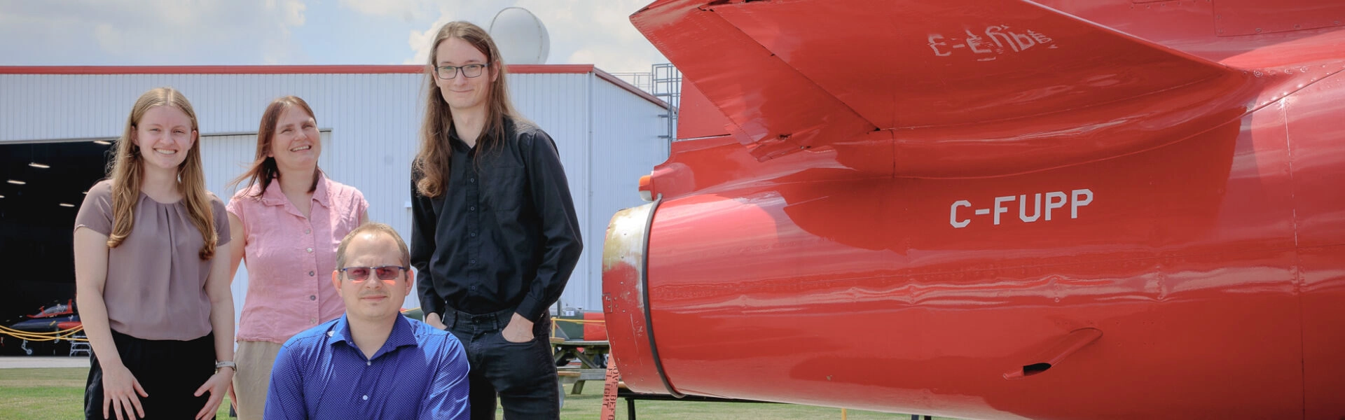 Photo of researchers posing on an airfield by a jet engine exhaust
