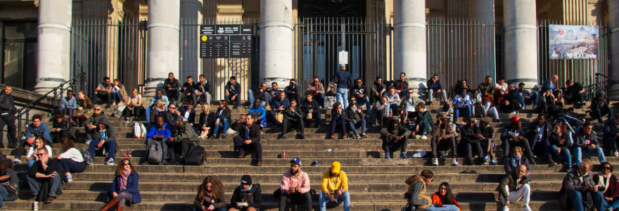 A crowd of people on the steps of an institutional building