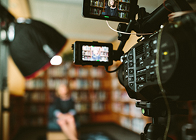 decorative image of a camera set up to interview a woman