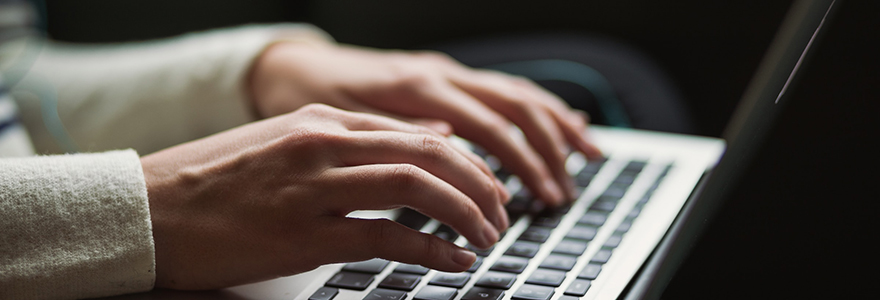 Hands typing on a laptop