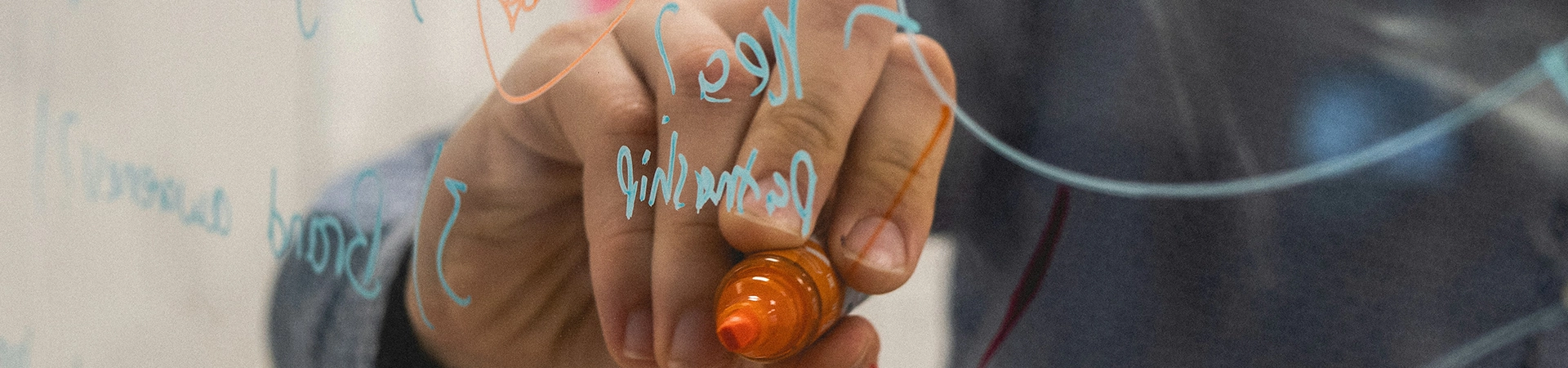 Someone writing on a clear whiteboard