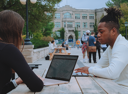 Students on laptops study outside on campus