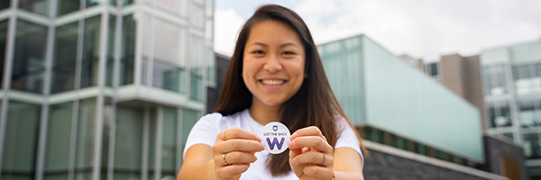 Student holding a sticker with a purple W and text reading Got the Shot