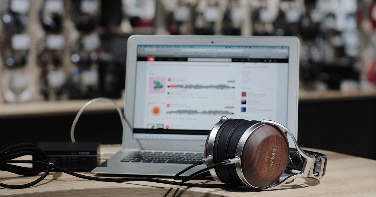 Grey and brown headphones sitting on a desk beside a laptop