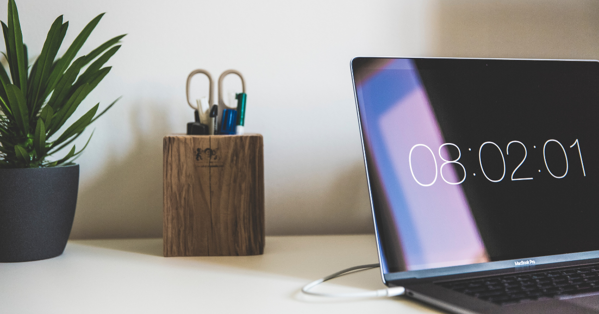 A laptop open on a desk with the time displaying