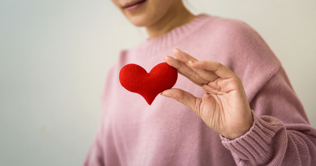 A person holding a red toy heart in their hand