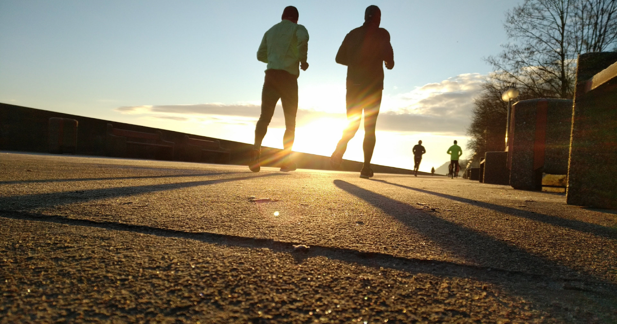 Two people running on a road in the early morning