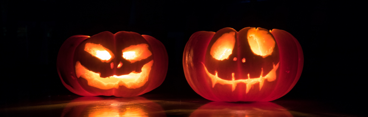 Two carved jack-o-lanterns sitting outside in the dark