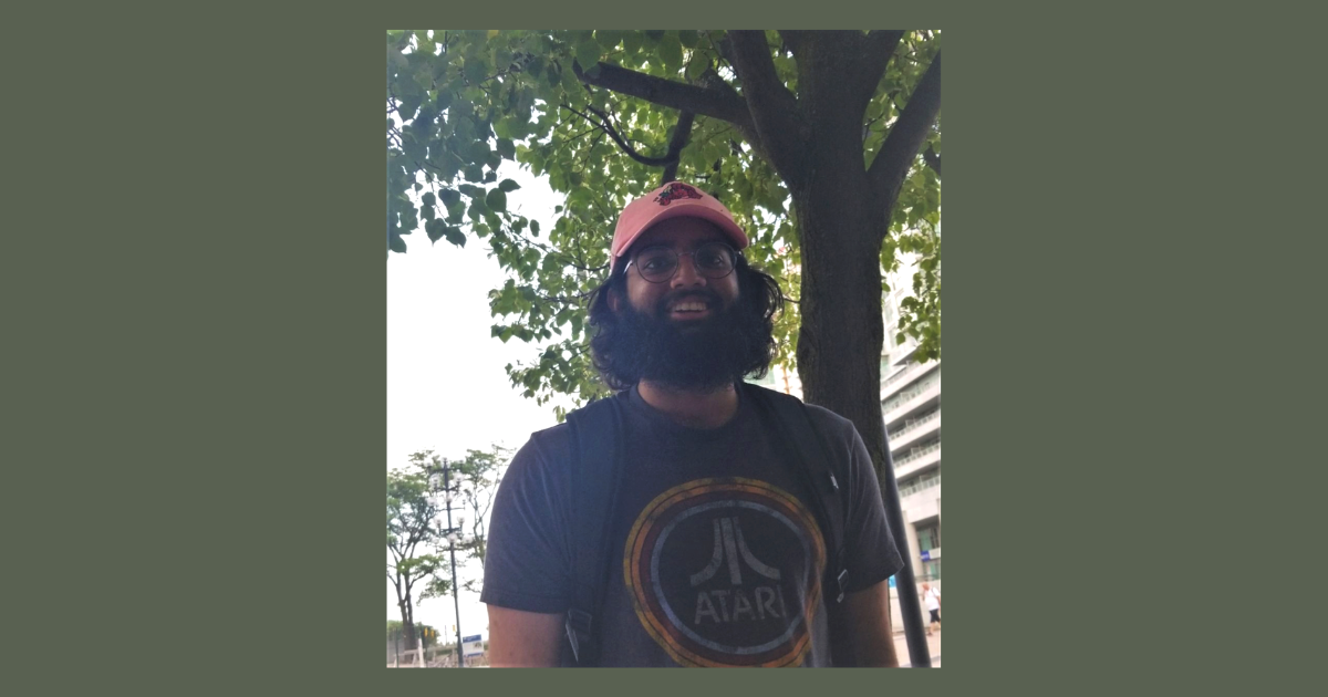 A photo of Josh standing outside in front of a tree