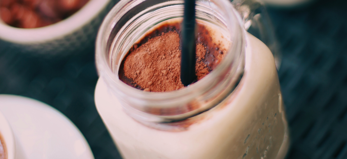 Chocolate protein shake in a clear jar with a straw for drinking
