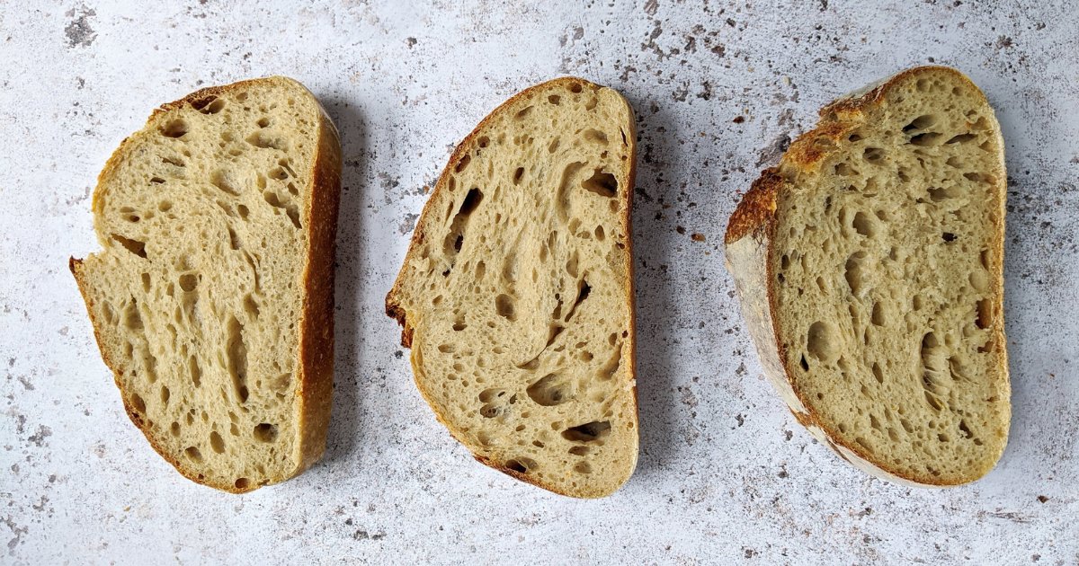 Three slices of fresh sourdough bread on a marble counter