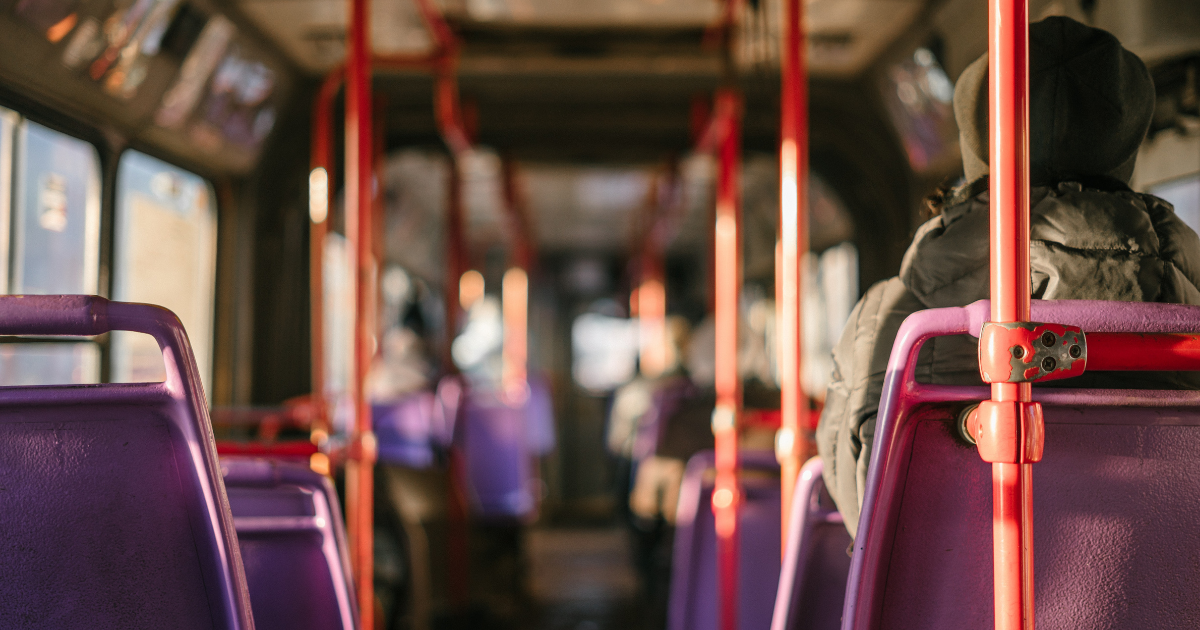 A person sitting on a city bus in the early morning sun