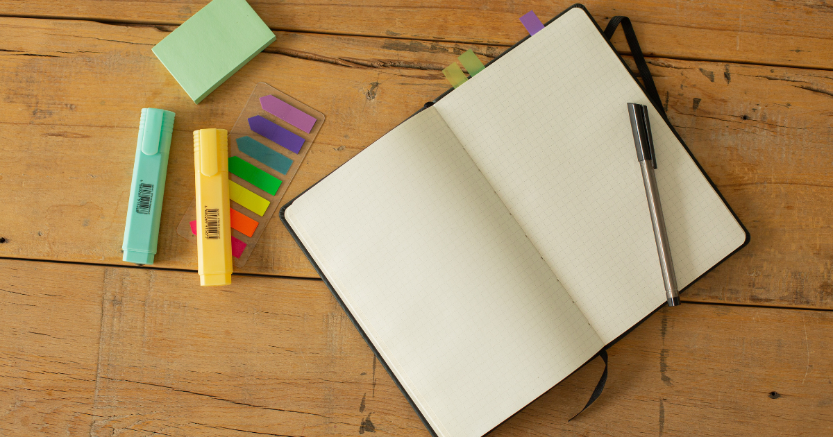 A photo of a notebook, pen, and sticky notes on a desk