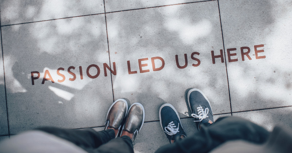 Two people standing on a gray tiled floor with the phrase "Passion Led Us Here" 