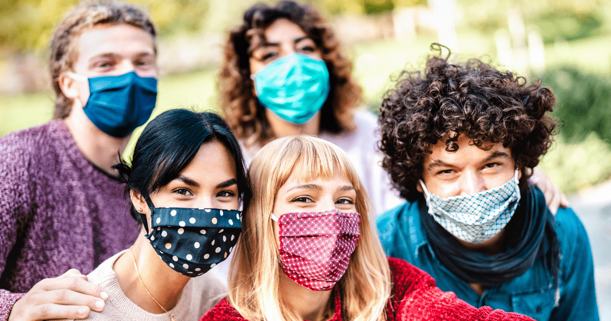 A group of friends huddled close together wearing face masks