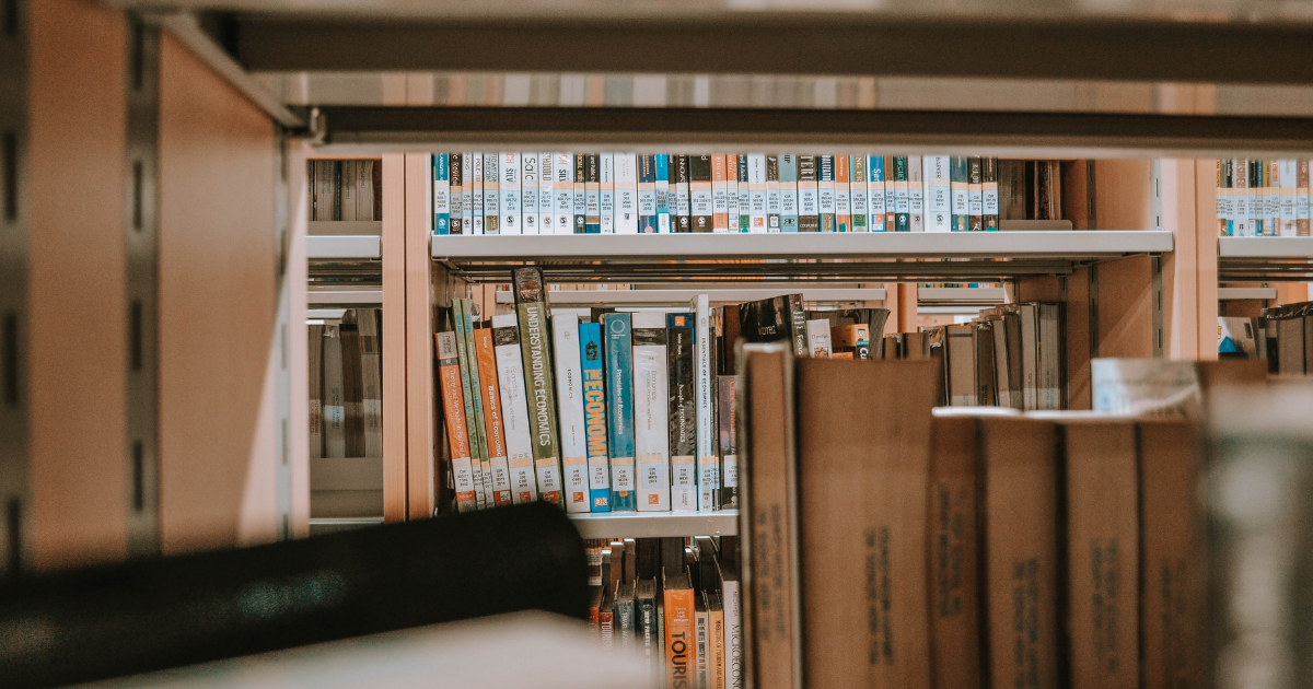 Books on a light brown shelf in a library