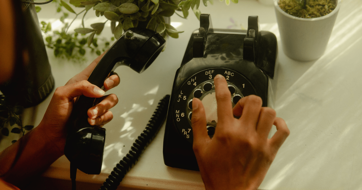A person dialling a number on an old rotary phone