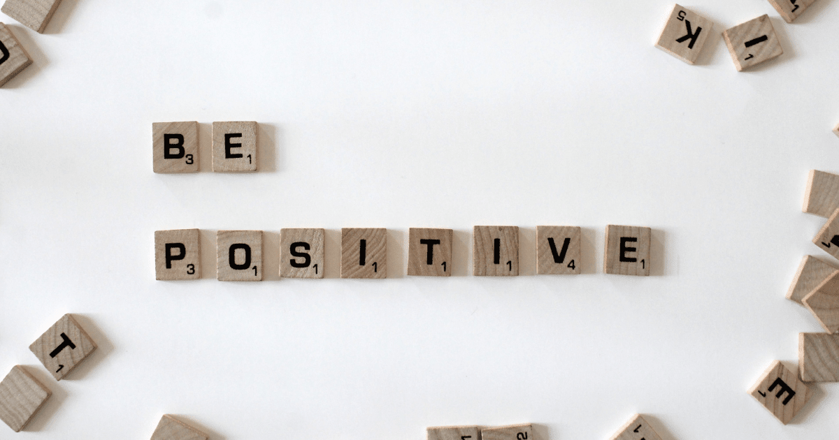 Scrabble tiles laid out on a white background reading "Be positive"