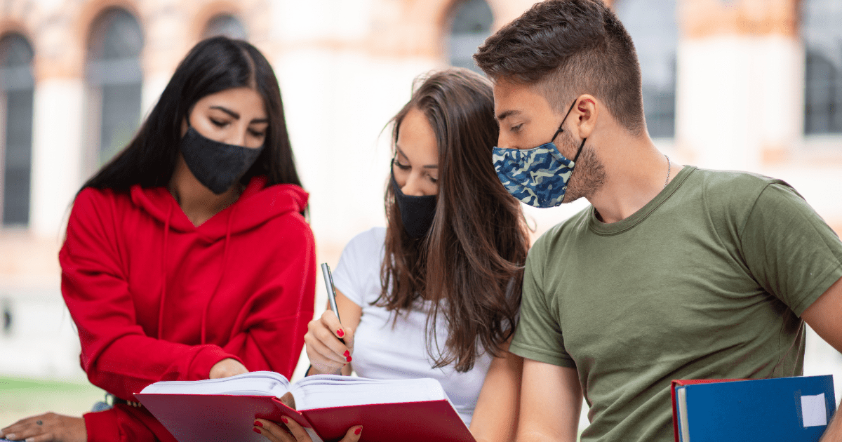 A group of students wearing masks studying together on a university campus