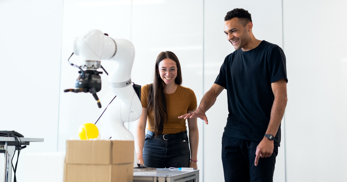 A photo of two students working in a lab with robotic equipment