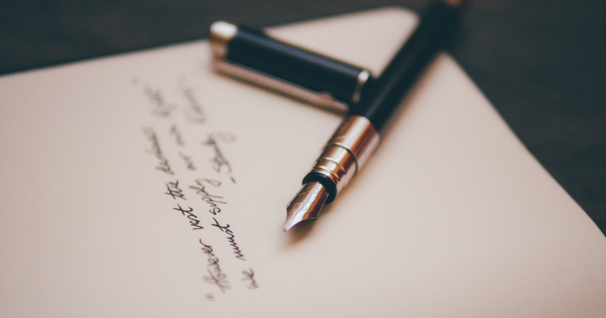 A photo of a fountain pen resting on a piece of white paper