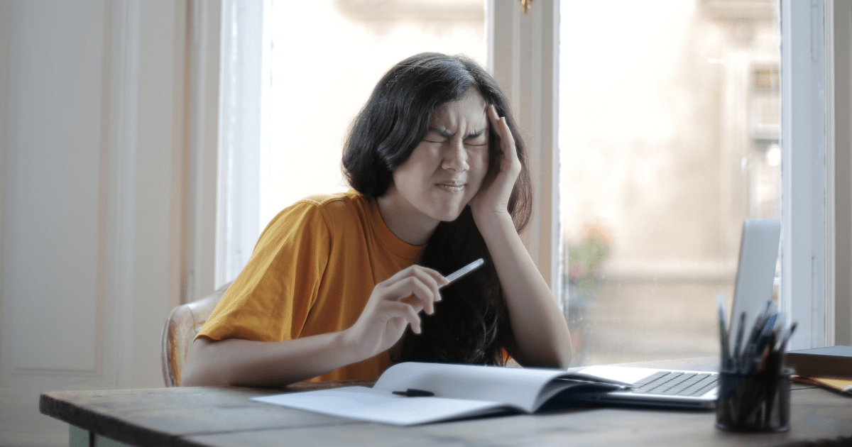 A person sitting at a desk feeling frustrated and stressed