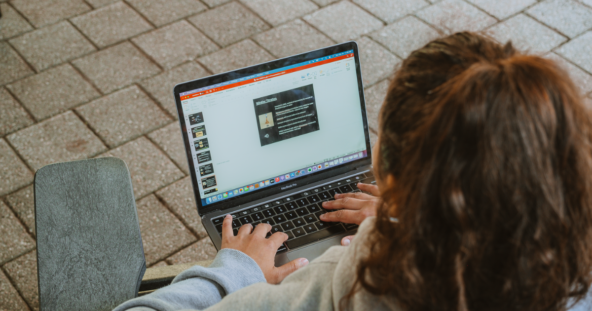 A person sitting in a chair with a laptop resting on their lap