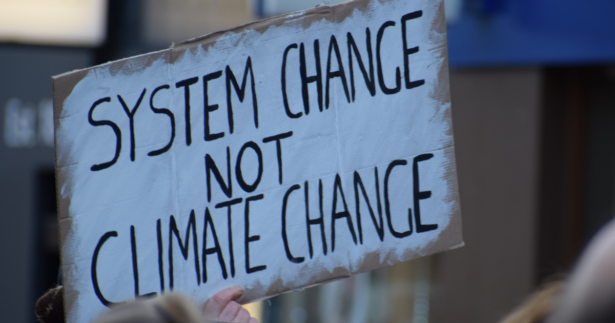 A close up of a sign that reads "System Change not Climate Change"