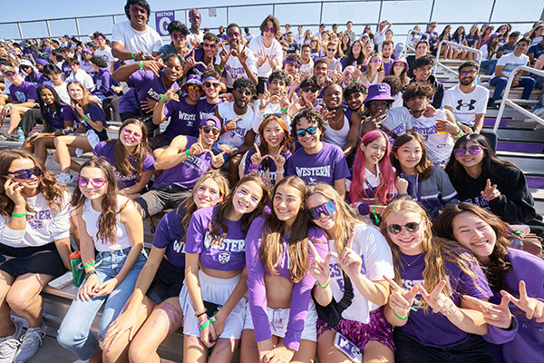 A group of student cheering on the Mustangs football team.