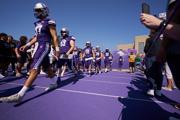 The Western football team entering alumni stadium field