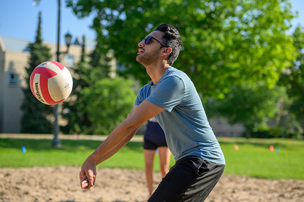 A student playing volleyball outside.