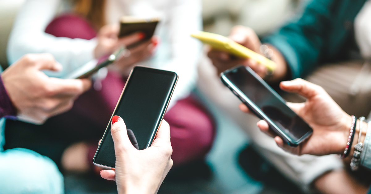 A group of people holding cellphones together in a circle.