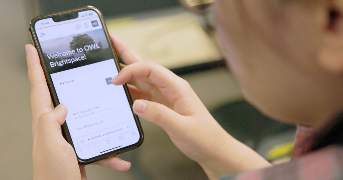 Someone holding a phone with the screen showing OWL Brightspace.