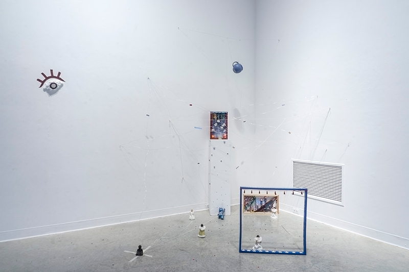 Photograph of an installationa plinth, wooden frame, white rope, and hanging teapot