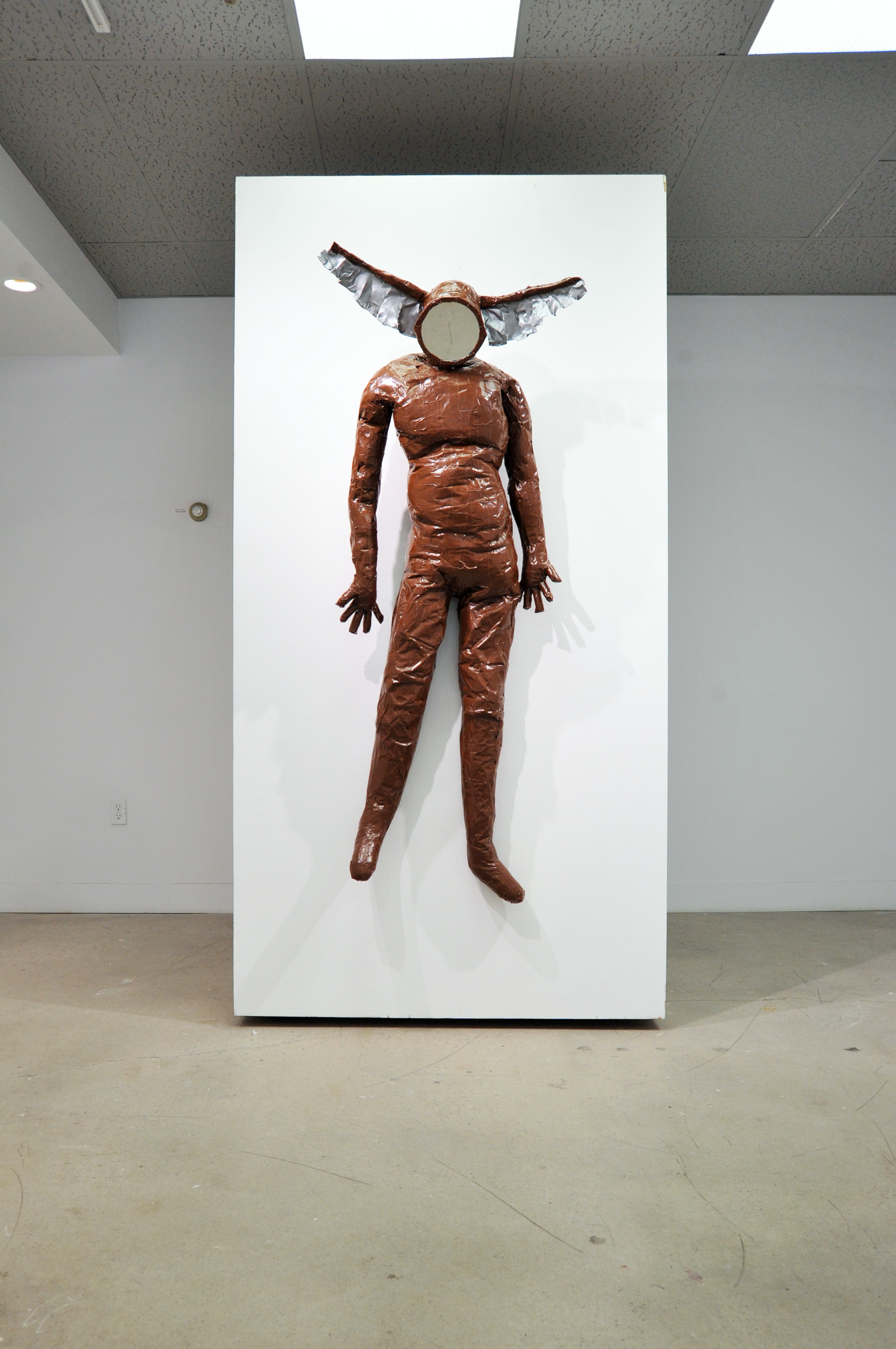 A humanoid sculpture with a blank face and large ears protruding from the sides of its head