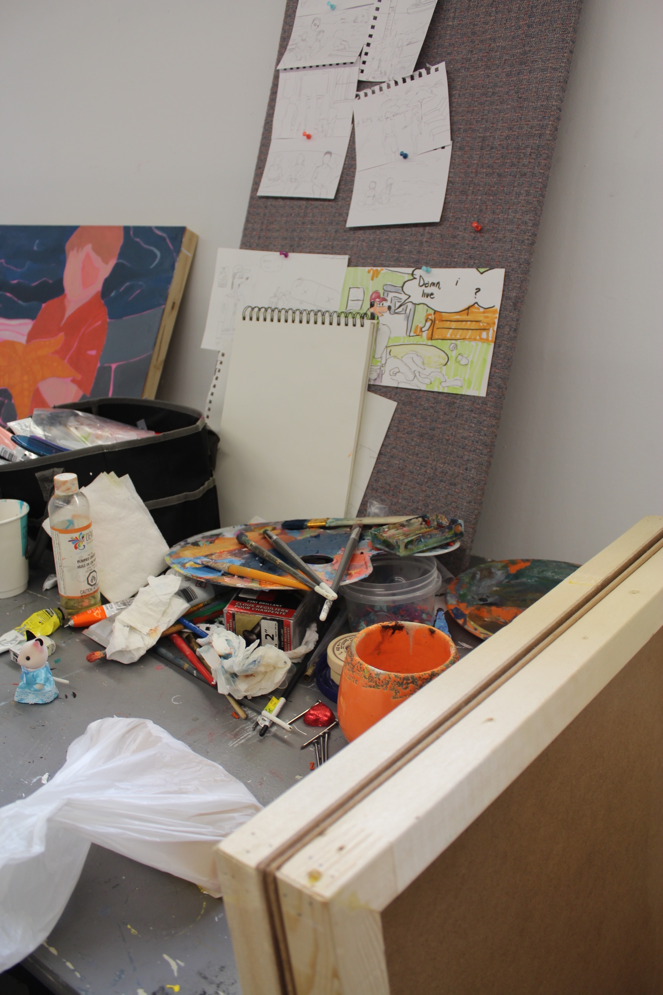 Photo of a pile of painting tools and sketches pinned to a board.