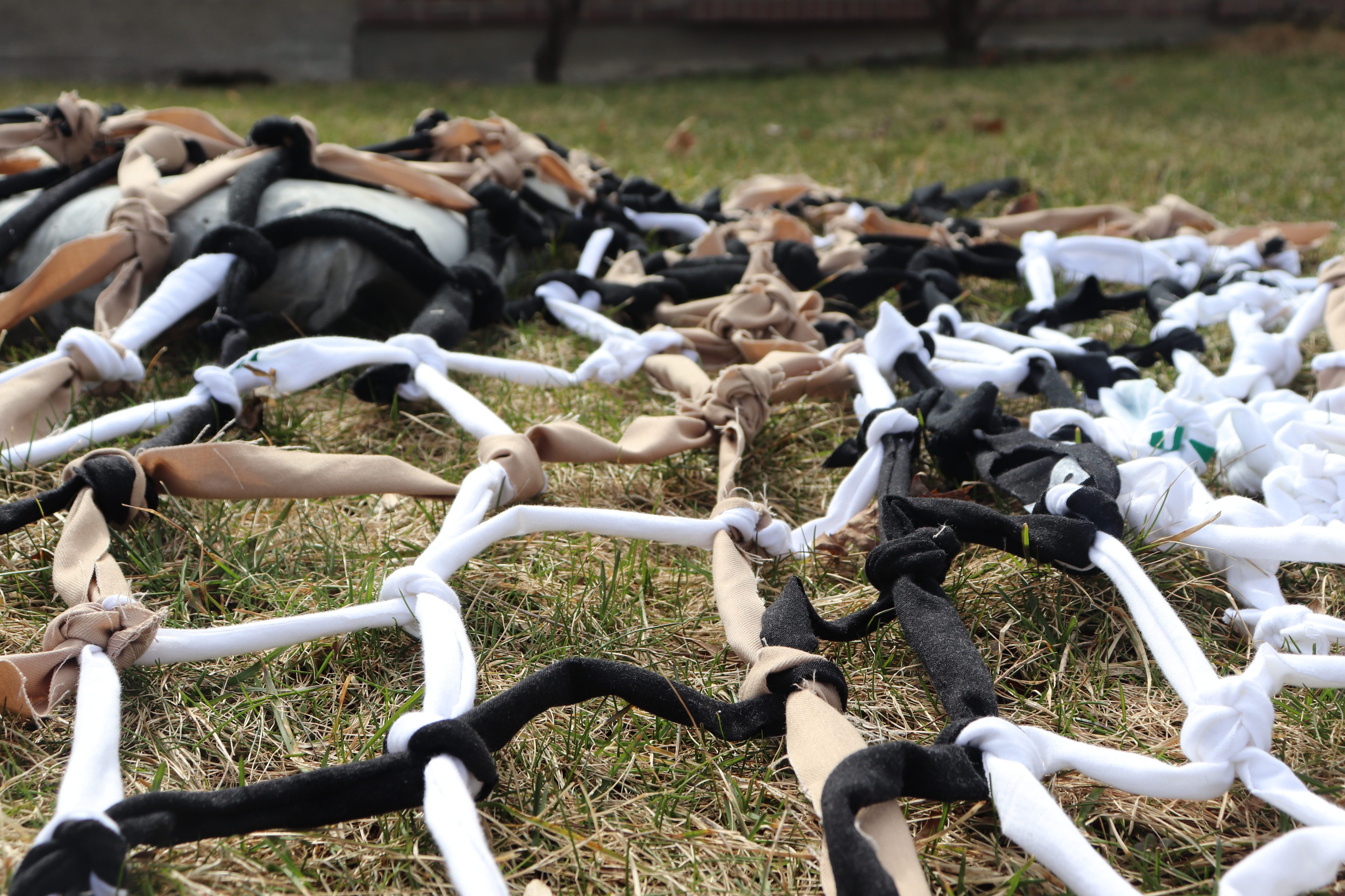 Photo of pieces of white, black, and tan-coloured fabric tied together to form a net.