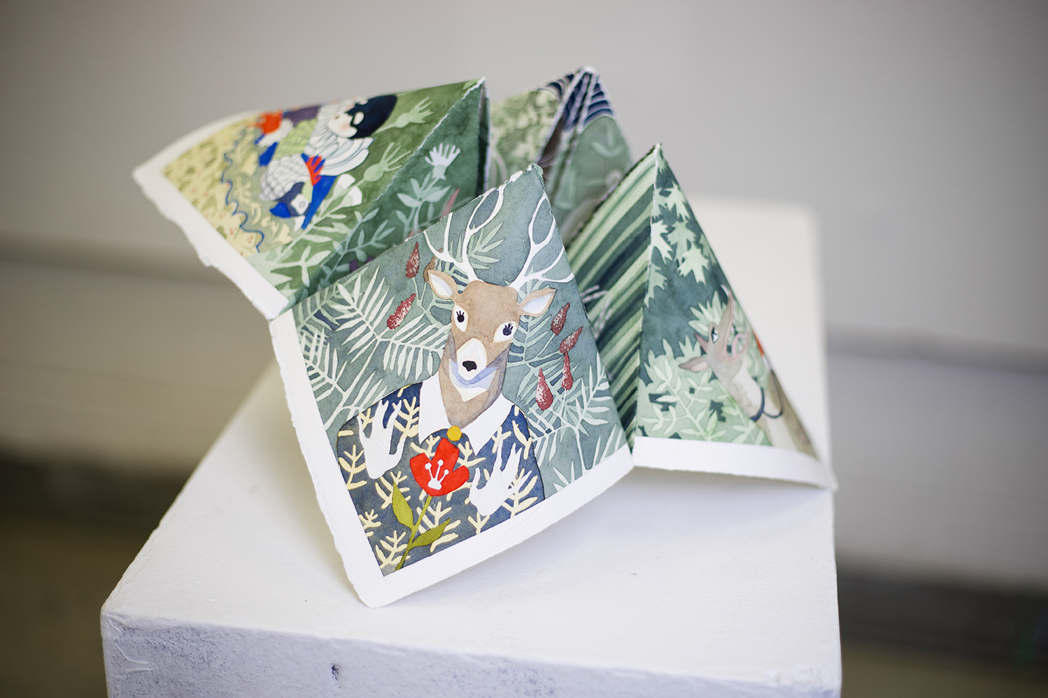 Photo of a paper cootie catcher with animals and scenes depicted on each of its corners.