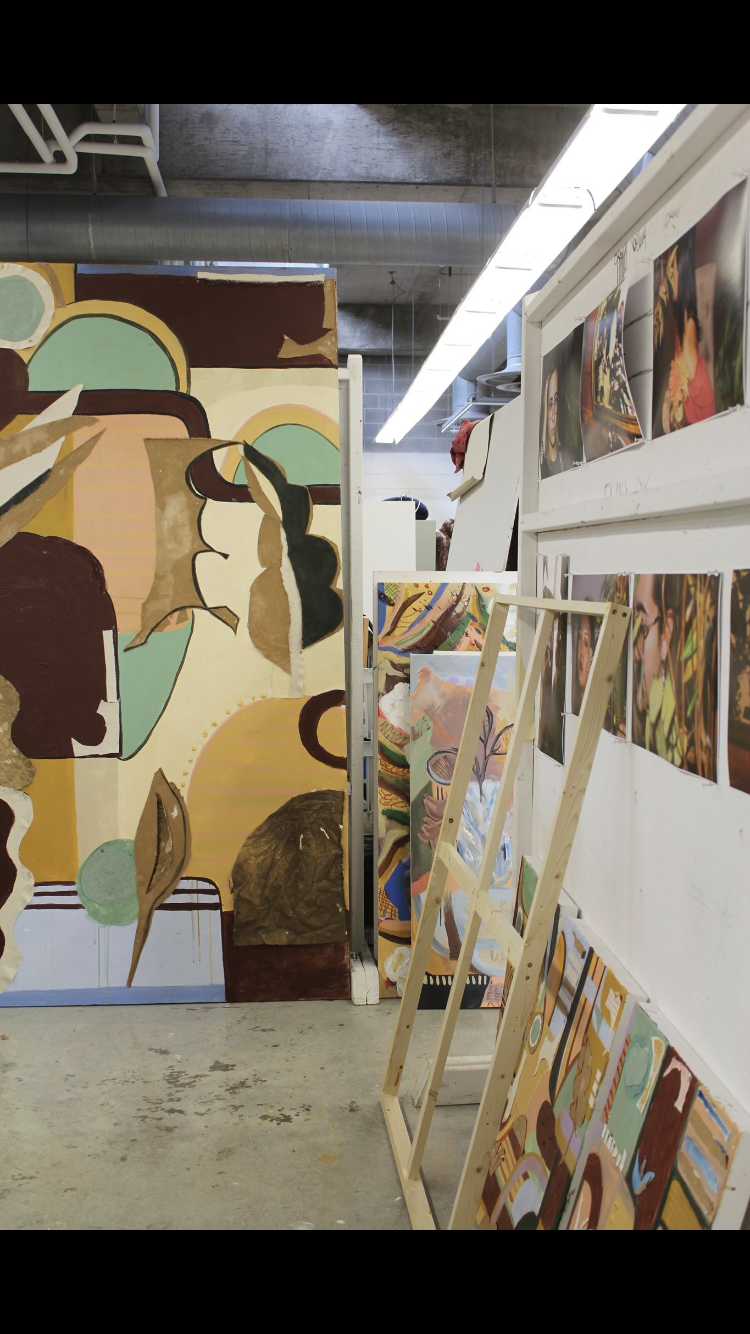 Photo of the artist's studio with paintings hanging on the wall for review.