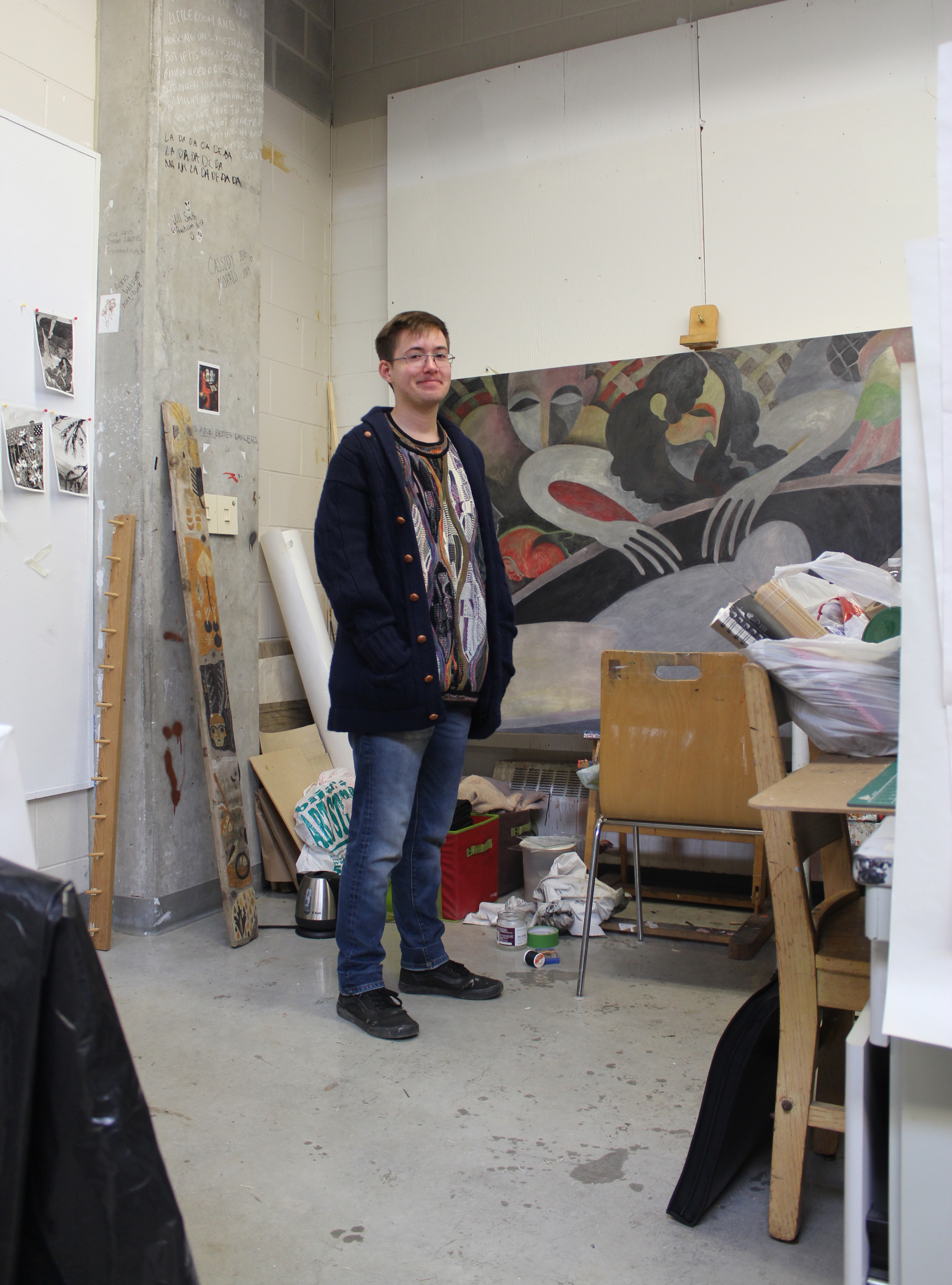 Reilly standing in their studio surrounded by artwork.