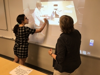 Dr. Sandi Spaulding shows a participant how to correct posture using the ceiling camera and whiteboard markers
